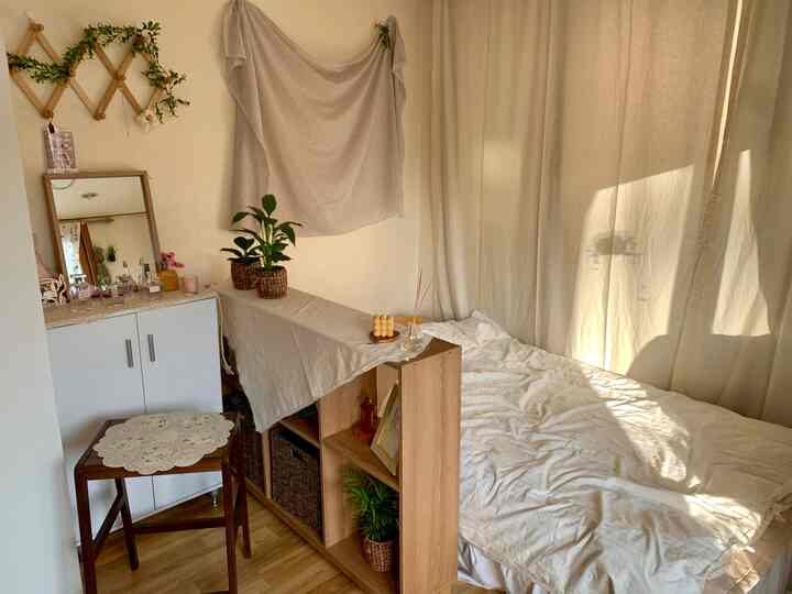 Cozy natural-toned small studio bedroom furnished with wood-tone furniture, plants and vintage decor