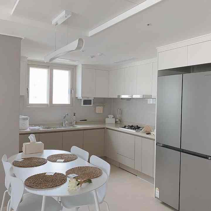 Modern living space with clean white kitchen and 4-person dining table prominently placed