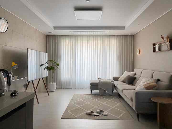 Warm living room with ivory and beige tones, featuring a sofa, rug, and curtains in a clean, natural interior