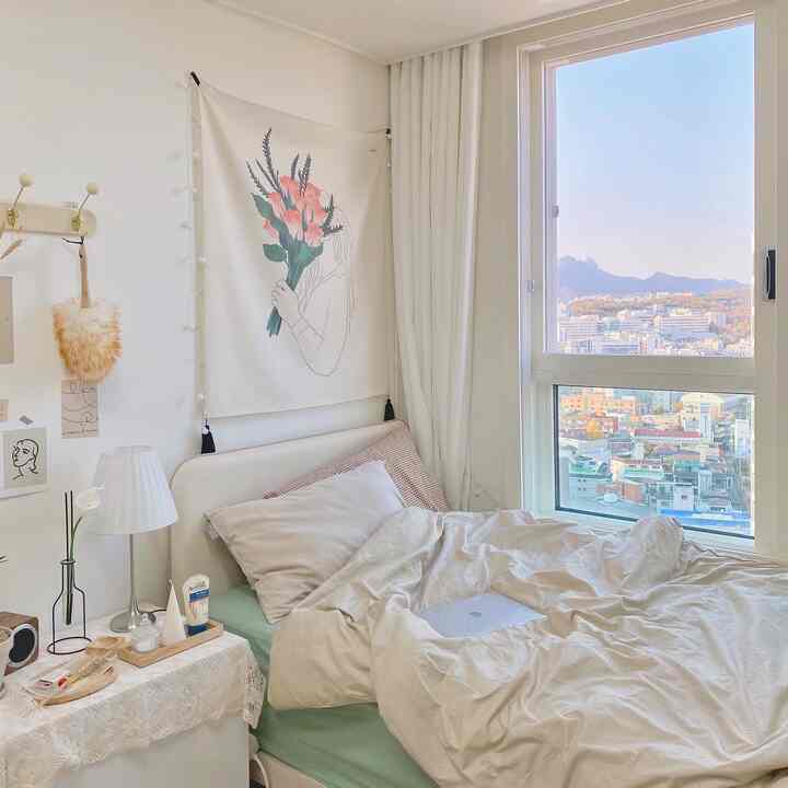 A cozy bedroom in soft beige and white tones featuring a comfortable bed and curtains