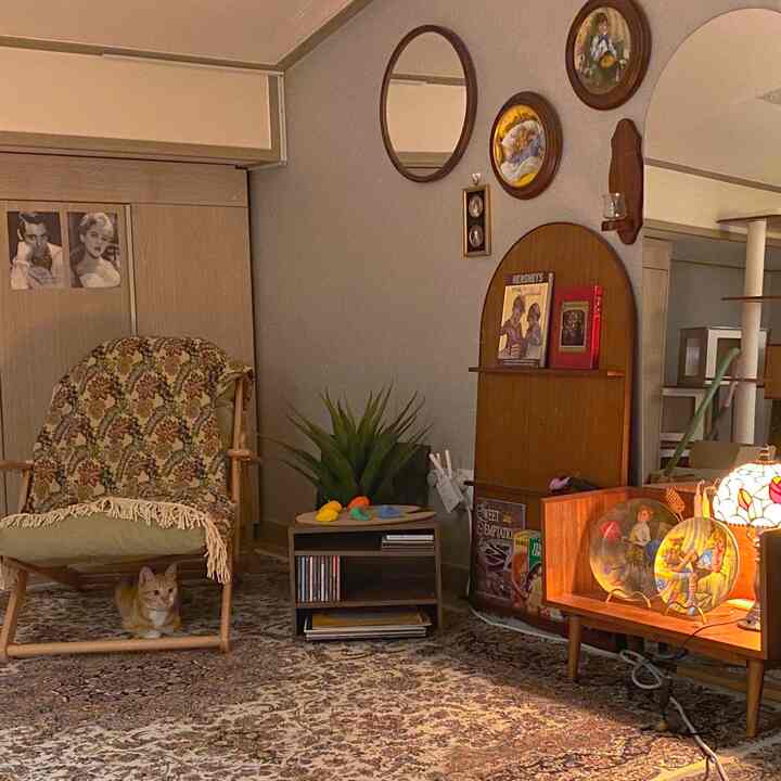 ベージュとブラウンの調和が取れたヴィンテージ風リビング、柄のあるカーペットとアームチェアが配置され、椅子の下に猫がいる印象的な空間