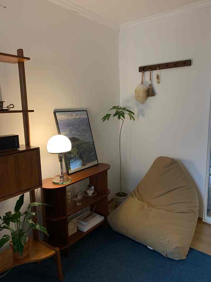 白い壁と木目調の家具、ベージュのビーズクッションソファ、ネイビーブルーのラグが調和するナチュラルな北欧リビング