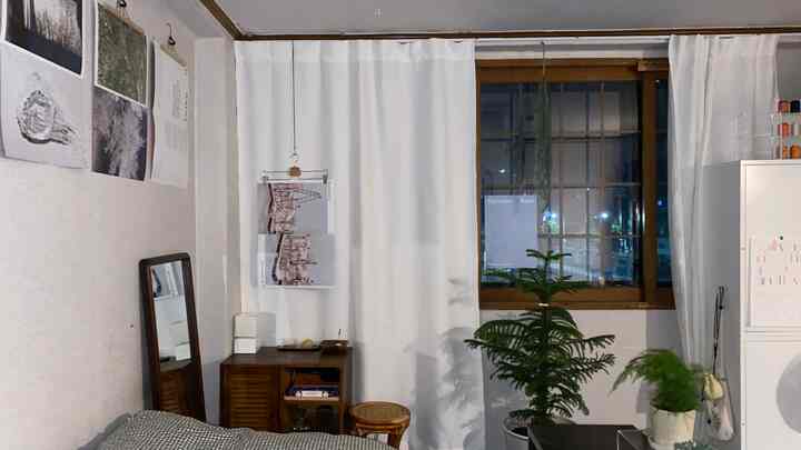 A small vintage room in white and wood tones, featuring blackout curtains and plants creating a cozy atmosphere in an old house
