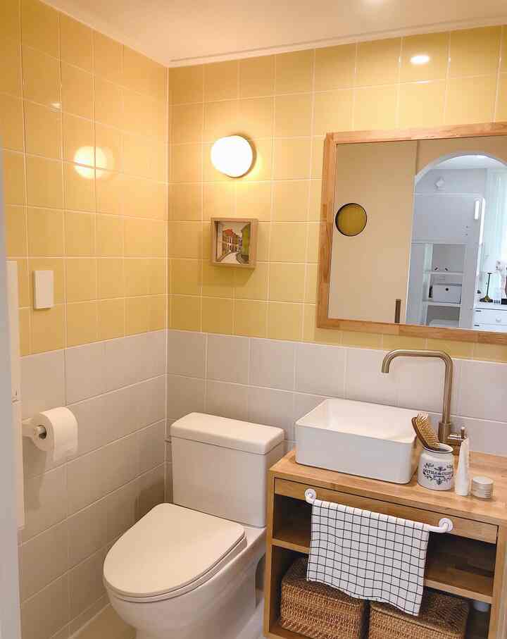 Yellow and white bathroom featuring wooden vanity and rattan baskets creating a warm, natural atmosphere