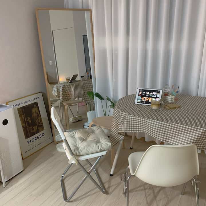 ナチュラルカラーとヴィンテージ要素が調和したワンルームダイニング、アットホームな雰囲気のテーブルと折りたたみ椅子が配置された印象的な空間