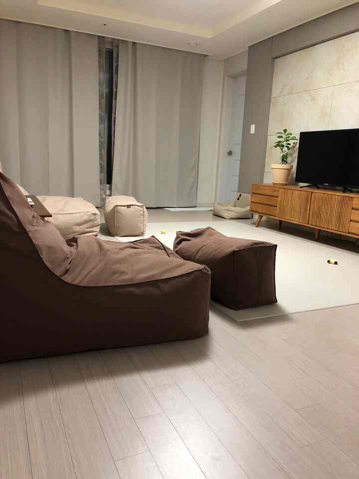 ブラウンのビーズクッションソファとアイボリーのラグが配置された、落ち着いた雰囲気のリビング