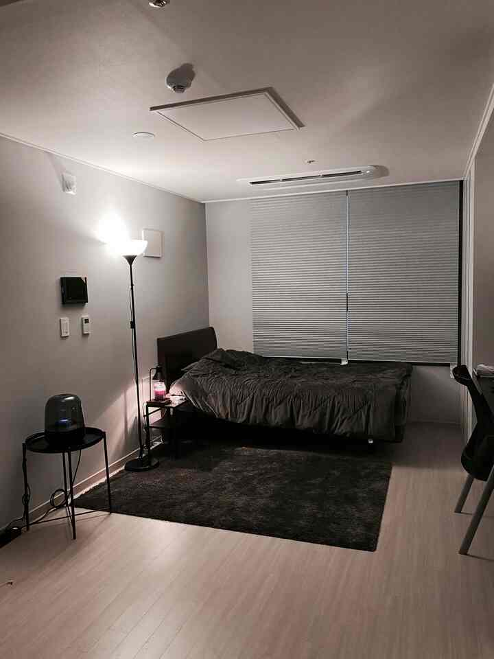 Monotone bedroom in charcoal and gray tones featuring nightstand and floor lamp with simple modern atmosphere