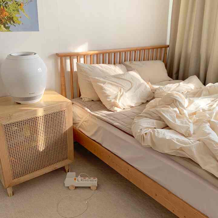 ベージュと木目調の新婚寝室、木製ベッドフレームと遮光カーテンが配置された落ち着いた自然な雰囲気のインテリア