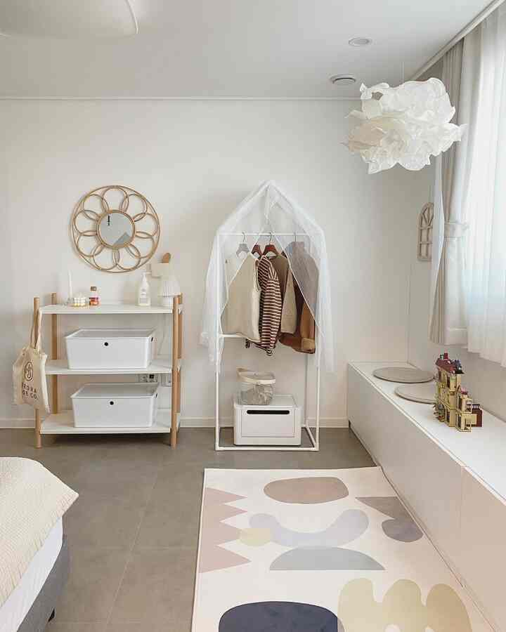 White and natural toned kids' room featuring neat storage units and a clothing rack in a simple, organized space