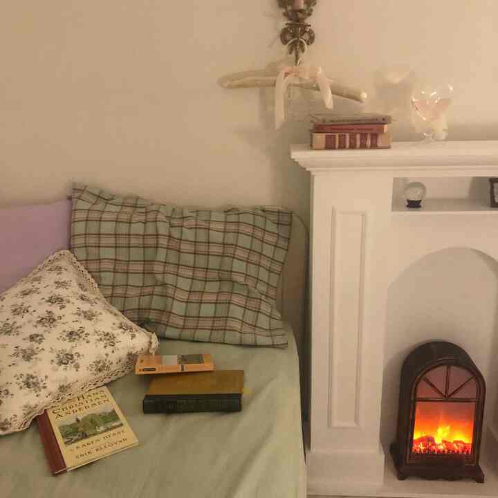 Soft beige and mint-toned bedroom featuring a vintage fireplace and cozy floral and plaid pillows