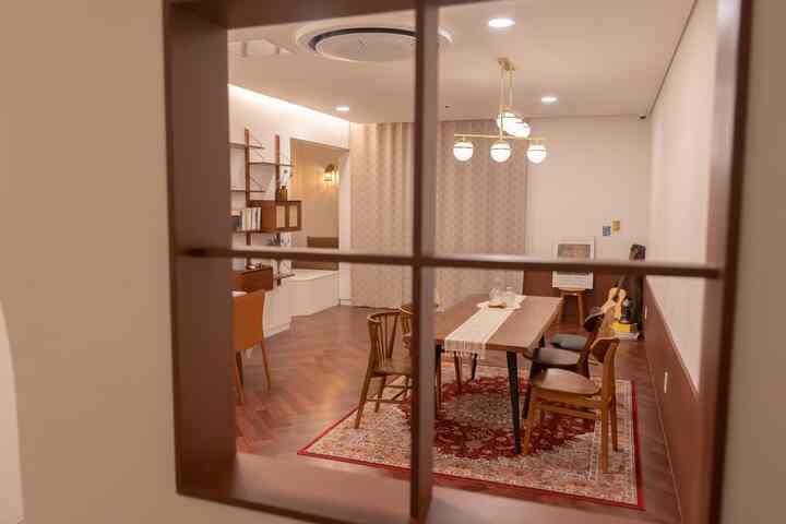 暖かいブラウン調のダイニングルーム、木製のダイニングテーブルと様々な椅子が並ぶカフェ風の雰囲気あるインテリア