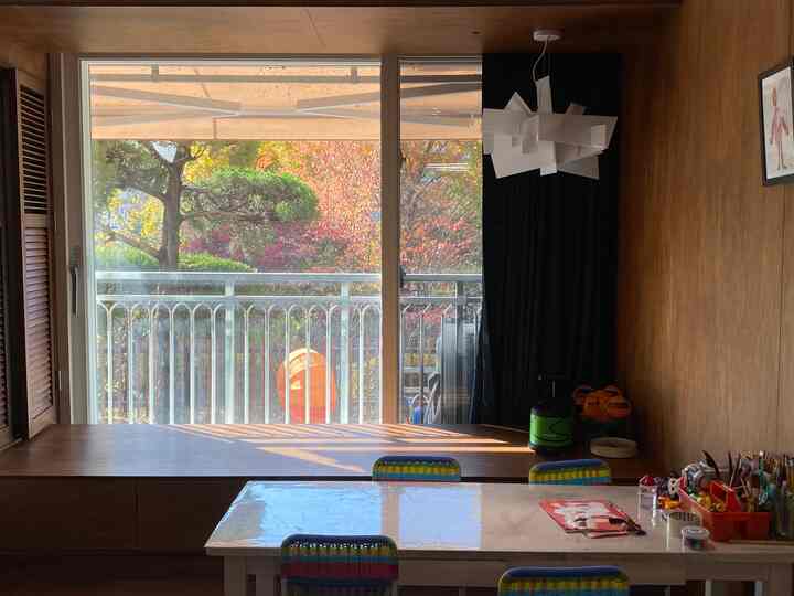 Warm brown toned kids' room featuring a large window with platform seating and kids' desk creating a cozy atmosphere