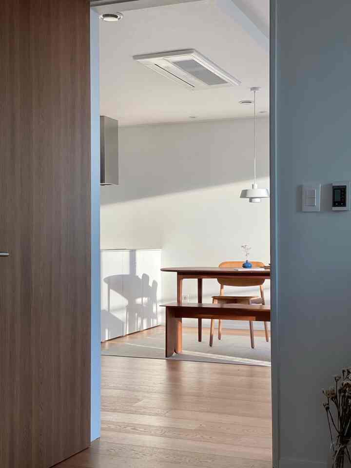 White and wood tone dining room featuring an oval wooden dining table and bench on a rug, creating a clean autumn atmosphere