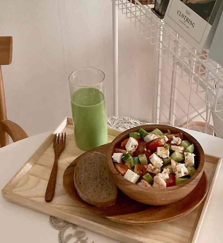 Cozy brunch setting featuring natural wood tones and green hues with a salad bowl and green smoothie on a table