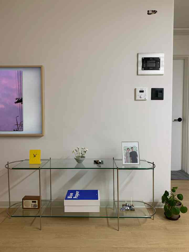 Natural color space featuring glass shelves, picture frame, small clock, and plant in a minimal and modern interior