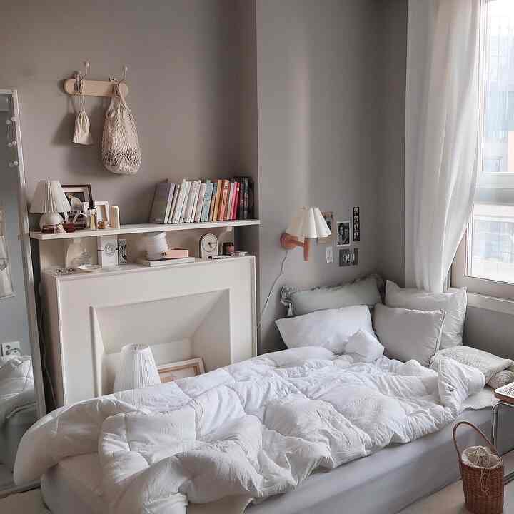 ベージュとホワイトの落ち着いた色調の寝室、窓際にカーテンと壁照明が配置された雰囲気のあるインテリア