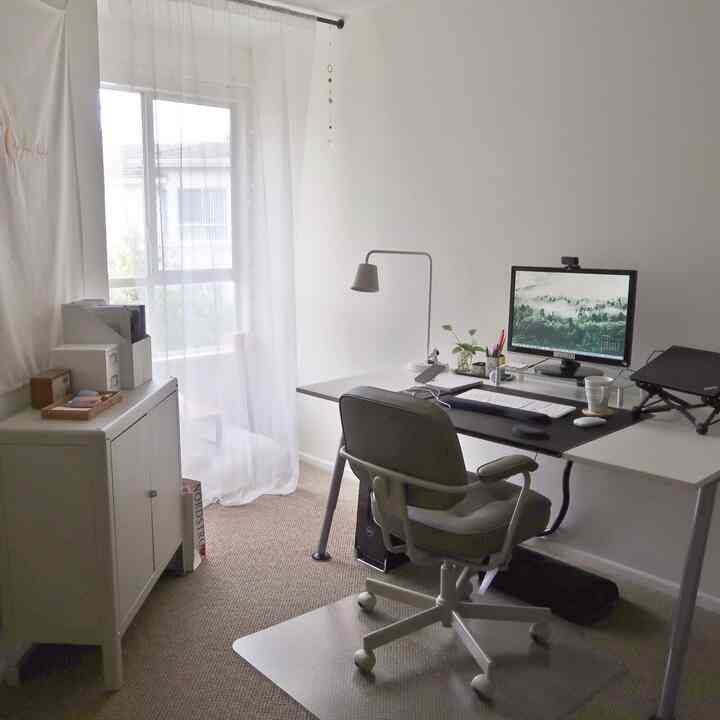 白とベージュのトーンのホームオフィス、コンピューターデスクとオフィスチェアが配置された清潔で明るい作業スペース