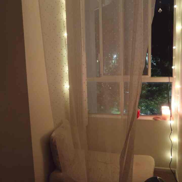 White and beige toned cozy nook by the window with curtains, cushions, and candles creating a warm, intimate atmosphere