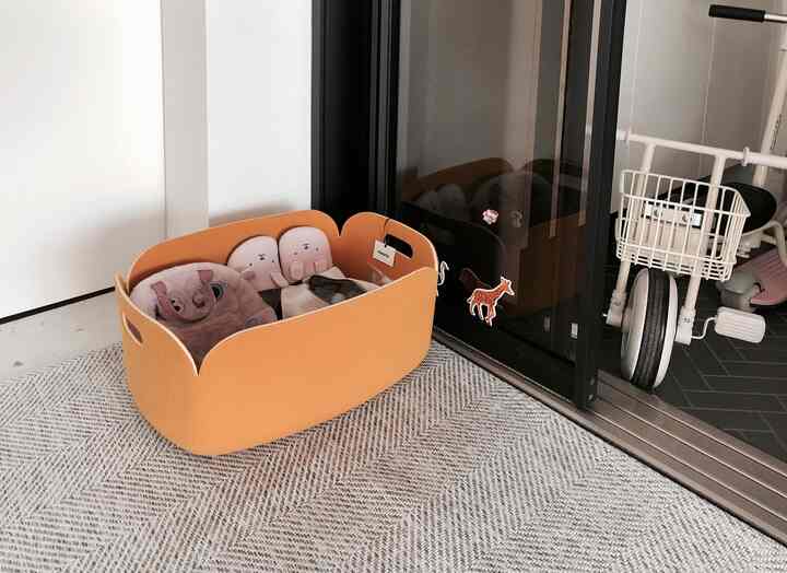 Natural color and beige-toned entrance featuring an orange storage basket and baby bike in a tidy organized interior