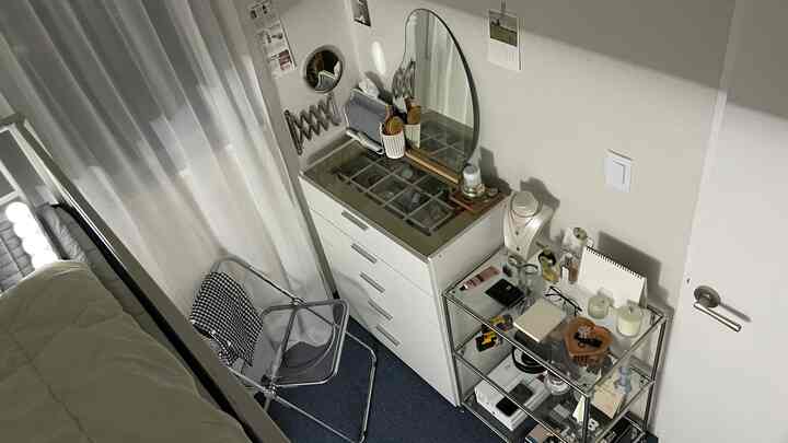 A compact bedroom with white and blue tones featuring mirrors and storage furniture in a minimalistic interior