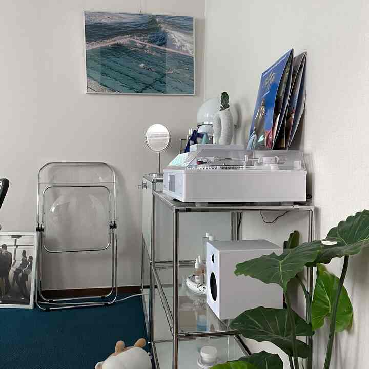 A compact space with dominant white and natural tones, featuring transparent chairs and audio equipment in a cozy and uncluttered interior