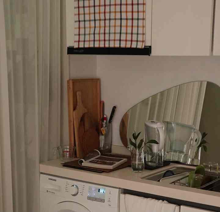 White and wood-toned kitchen featuring a mirror and various kitchenware arranged in a cozy space
