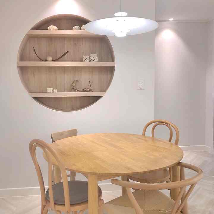 ナチュラルな木目調と白を基調としたダイニング、円形テーブルとイス、丸い壁棚が配置されたモダンな雰囲気のインテリア