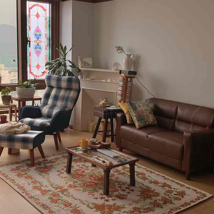 Beige-toned walls and floor with brown sofa and blue checkered armchair in cozy living room space