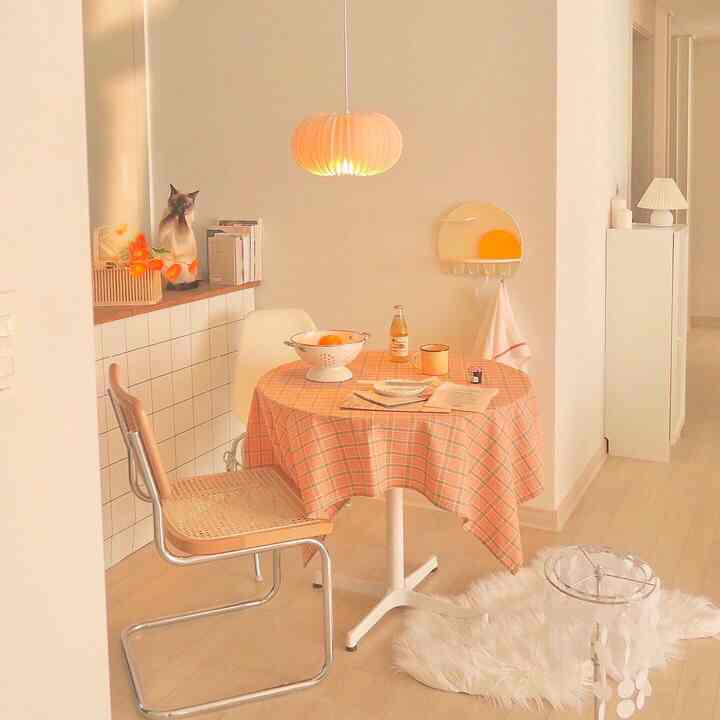 White and natural tone kitchen space featuring a round table with checkered tablecloth and cozy home cafe interior