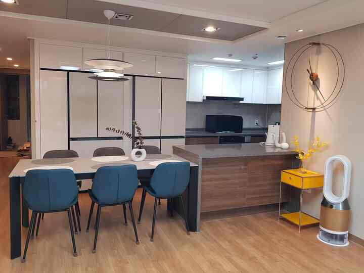 Modern kitchen and dining room with white and wood tones, featuring a central dining table and chairs in a clean setting