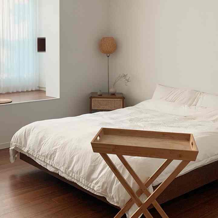 Natural bedroom with white walls and bedding, complemented by brown wood-tone floor and furniture creating a serene atmosphere