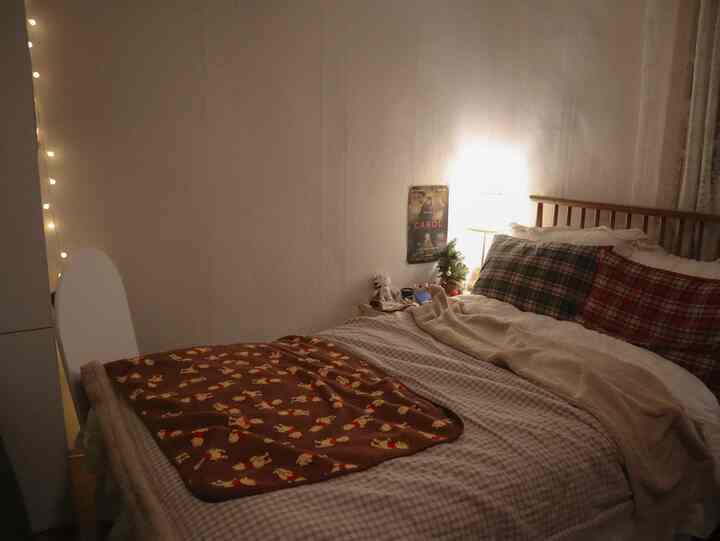 White and brown toned bedroom featuring a wooden bed with cozy blankets, creating a warm atmosphere