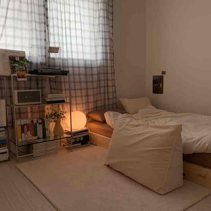 Natural beige-toned bedroom with low bed and chrome shelving unit creating cozy atmosphere