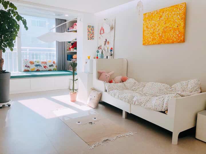 Bright white toned kids' room featuring a window seat and a white bed with a modern interior
