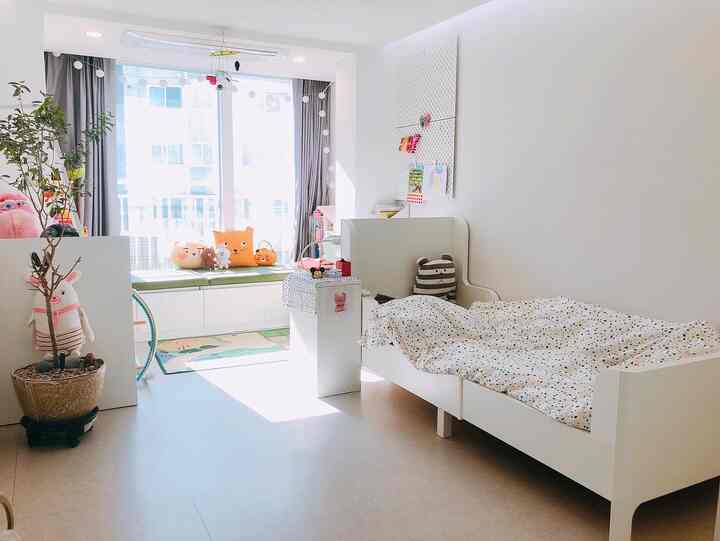 Bright and cozy kids' room in white tones featuring a children's bed and window storage bench