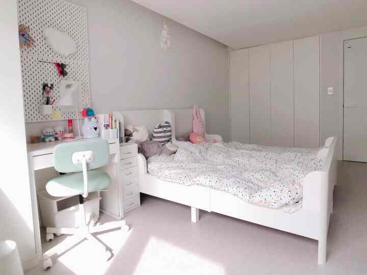 White-toned kids' room featuring two beds and a desk arranged in a clean modern space