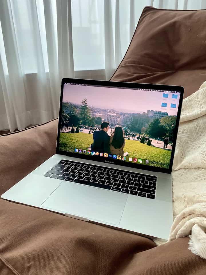 Cozy living room with soft brown bean bag, cream throw blanket, white curtains, and a laptop indicating a home office setup