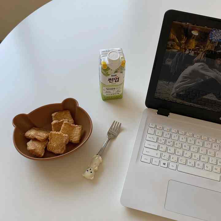 白いテーブルの上にクマ形のお皿とフォーク、飲み物が置かれた心地よいホームオフィスの空間