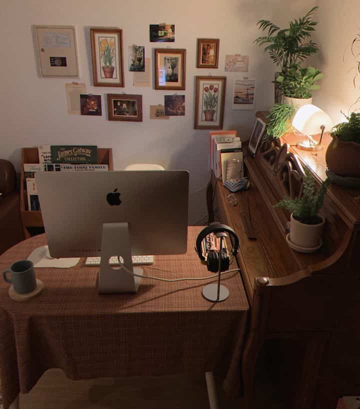 Warm brown wood-toned home office featuring a wall filled with picture frames and plants, alongside a wooden piano creating a cozy atmosphere