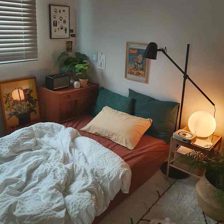 Cozy natural-tone small bedroom featuring wood furniture, mood lighting, and plants arranged warmly