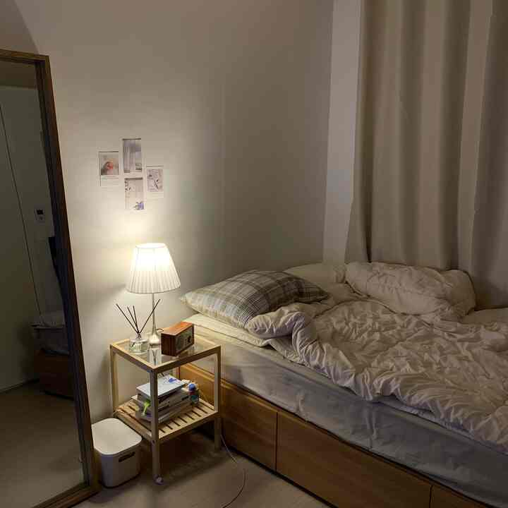 Natural-tone bedroom featuring wooden nightstand and blackout curtain with cozy single household setup