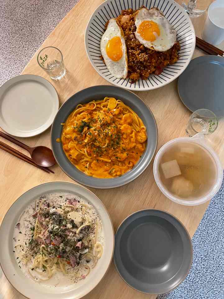 Natural wood-tone dining table featuring colorful bowls of food and clean home dining setting