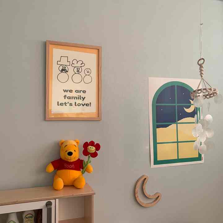 Light sky-blue walled kids' room featuring wooden furniture, cozy posters, and a plush toy creating a warm atmosphere