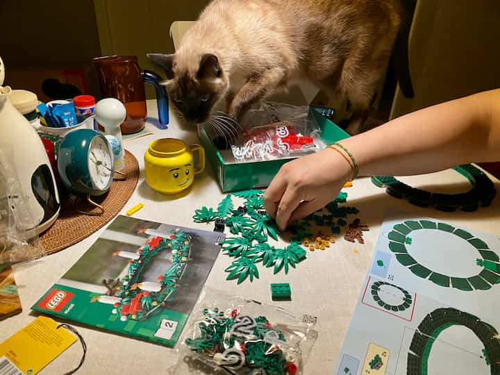 White table featuring Lego assembly, a clock, and a cat creating a warm home cafe atmosphere