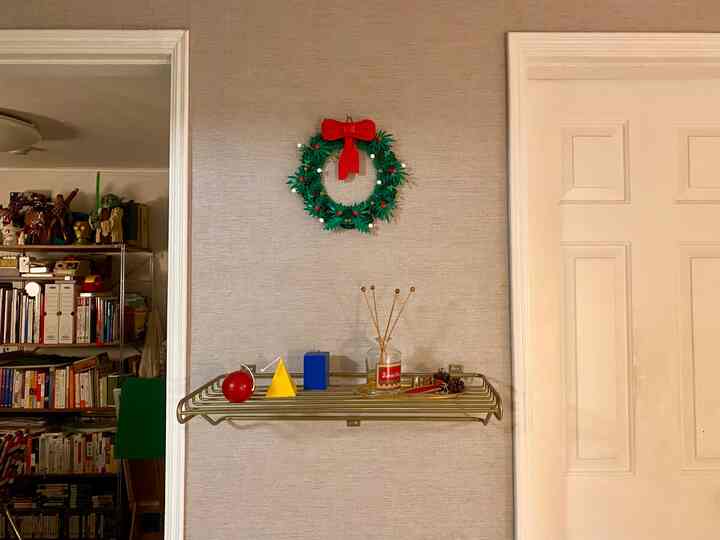 ベージュの壁にゴールドの棚とクリスマスリースが配置された雰囲気のある空間