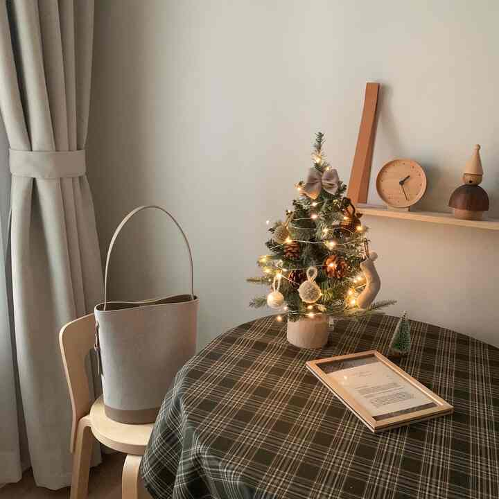 Beige-toned living space featuring wood accents and a small decorated Christmas tree creating a cozy atmosphere