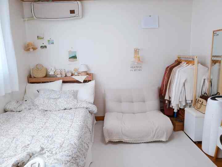 Bright white and natural wood-tone studio bedroom for single occupant, cozy and clean atmosphere