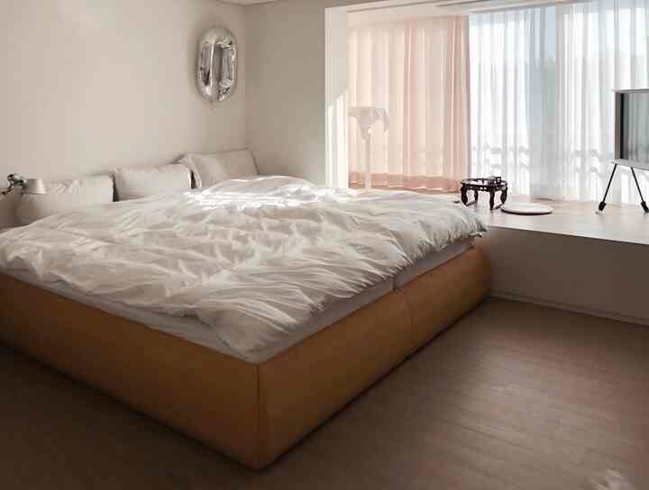 Cozy bedroom featuring soft yellow bed frame and white bedding with curtains allowing natural light