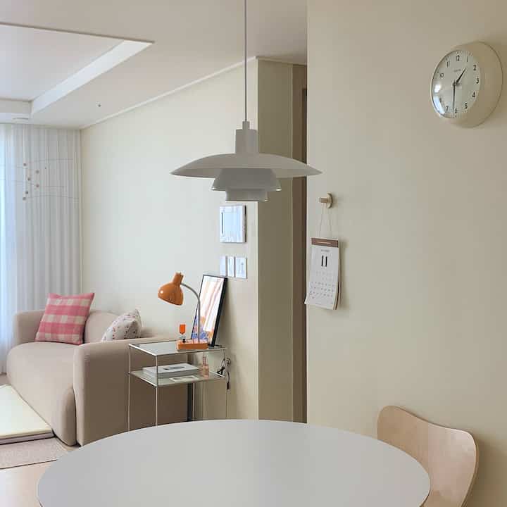 Soft beige and white-toned kitchen space featuring a round dining table and pendant lighting with a sofa, styled simply