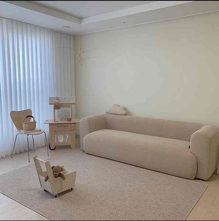 A soft beige-toned living room featuring fabric sofa and baby toys in a natural modern style space